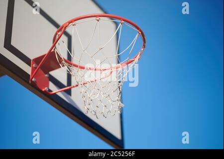 Basketball-Spiel Thema. Rote Rinf mit Netz und Brett auf blauem Himmel Hintergrund Stockfoto