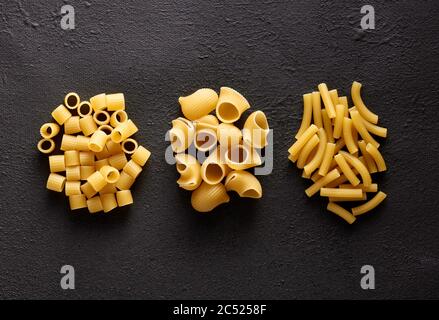Vielfalt an rohen Nudeln auf braunem texturierten Hintergrund. Flache Lay-Ansicht. Stockfoto