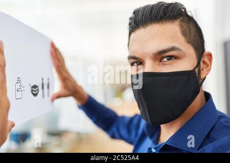 Geschäftsmann mit Gesichtsmaske befestigt Hygienevorschriften als Prävention gegen Coronavirus und Covid-19 Stockfoto