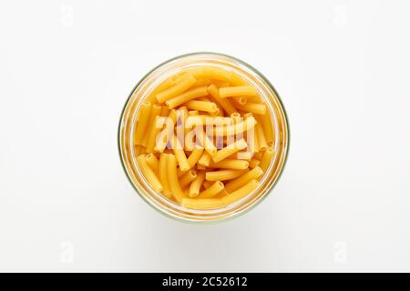 Ziti rigati oder Tubini Pasta in einem Glas auf weißem Hintergrund. Ansicht von oben. Stockfoto