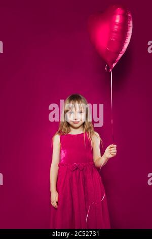 Happy Kind Mädchen hält Ballon Herz auf bunten rosa Hintergrund Stockfoto