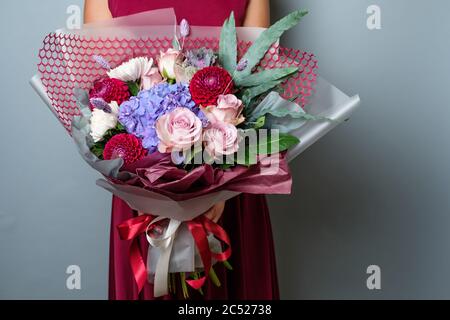 Schöner Strauß in weiblichen Händen isoliert auf grauem Hintergrund. Stockfoto