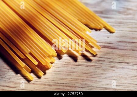 Haufen roher Spaghetti auf texturiertem Holzküchentisch. Makroansicht. Stockfoto