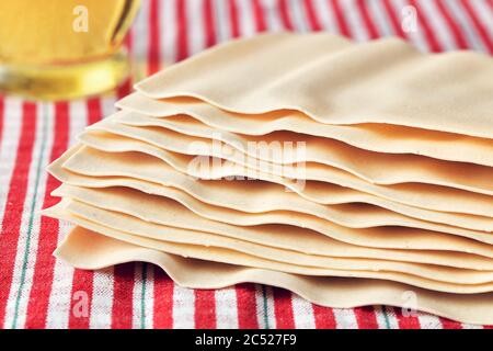 Getrocknete Lasagne Pasta-Blätter mit Olivenöl-Flasche auf einer Tischdecke. Makroansicht. Stockfoto