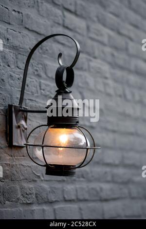Vintage schwarze Lampe leuchtet schwach außerhalb des dunklen Backsteingebäudes. Stockfoto