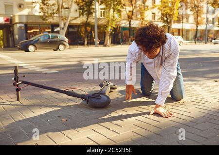 Unfall mit einem elektrischen scooter. Ein Mann fiel von einem Motorroller auf einer Straße der Stadt. Stockfoto