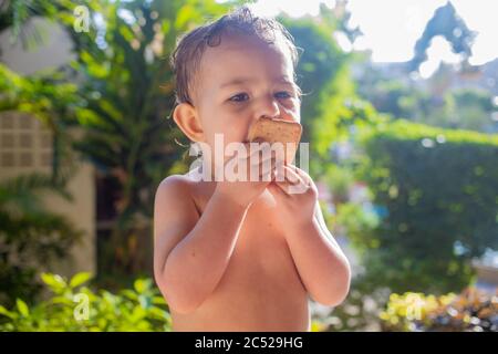 Nettes Kleinkind mit Appetit essen Cookies an einem sonnigen Tag Stockfoto