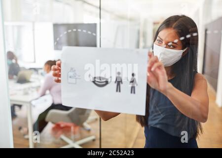 Business Frau mit Alltagsmaske fastet Tafel mit Verhaltensregeln gegen Infektion mit Covid-19 Stockfoto