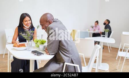 Geschäftsleute sitzen an separaten Tischen in der Cafeteria, um wegen Covid-19 Abstand zu halten Stockfoto