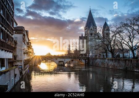 Atemberaubender Sonnenuntergang in der Nähe von Kirche und Brücke in Metz, Frankreich. Stockfoto