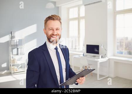 Positive Geschäftsmann Arbeiter Manager hält ein Clipboard in der Hand lächelnd arbeitet in modernen Büro. Stockfoto