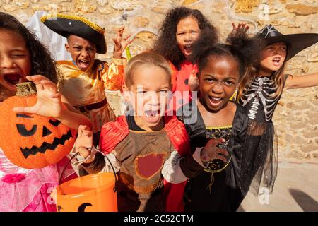 Viele Kinder schreien und schauen in Halloween Kostümen in einer Gruppe von Freunden zusammen auf die Kamera Stockfoto