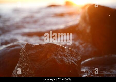 Steinige Strandsteine und Felsen, die abends in der Nähe beleuchtet sind, Sonnenuntergang und Sonnenaufgang Stockfoto