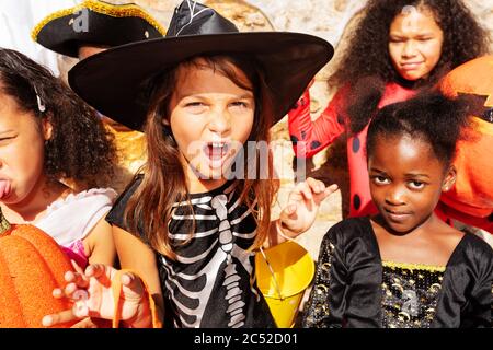 Close Portrait des Mädchens über große Gruppe von Kindern Jungen und Mädchen in Halloween-Kostümen stehen zusammen lächelnd zeigen gruselige Gesten auf Kamera schauen Stockfoto