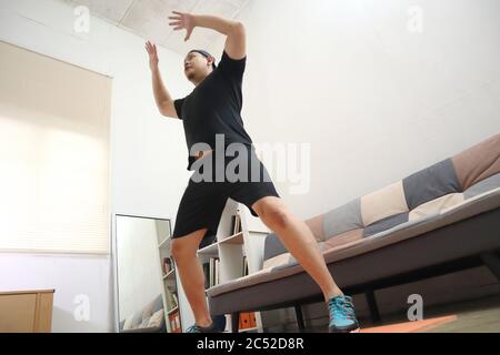 Asiatische männliche tun Übung zu Hause, um gesund zu bleiben auf neue normale Lebensweise, Indoor-Home-Workout-Konzept, Körpergewicht Cardio-Kreislauf-Training Stockfoto