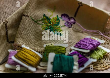 Papierspulen aus bunten Fäden und ein besticktes Stück Stoff Stockfoto