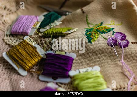 Papierspulen aus bunten Fäden und ein besticktes Stück Stoff Stockfoto
