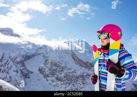 Schließen Side Portrait von niedlichen Mädchen in rosa Helm und Farbe Ski, Brille über hohen Bergspitzen Stockfoto