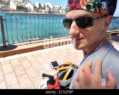 Frauenhand auf der Schulter eines Radfahrers, St Paul's Bay, Malta Stockfoto