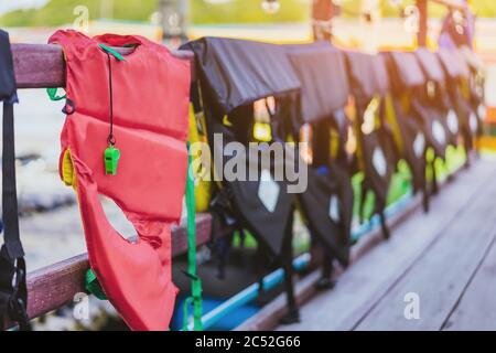 Eine grüne Pfeife mit roter Lebensjacke, die am Geländer um den Gehweg hängt, damit die Passagiere sicher an den Docks sind. Stockfoto