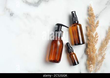 Bernstein Glas kosmetische Flaschen und trockene Blumen auf Marmor Hintergrund. Set von natürlichen Bio-SPA-Beauty-Produkte Stockfoto