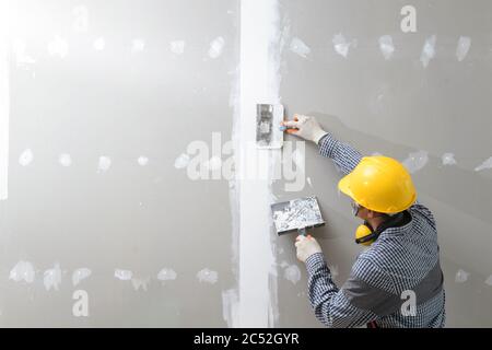 Rear view of a plasterer plastering walls Stockfoto