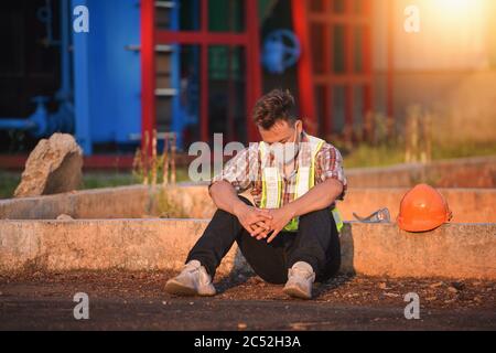 Bauarbeiter trägt eine Gesichtsmaske auf dem Boden sitzend, Thailand Stockfoto