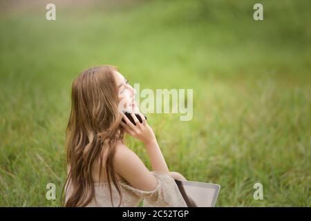 Frau auf einem Feld sitzend, die am Telefon spricht, Thailand Stockfoto