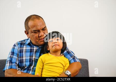 Seniorbürger kuschelt mit seiner Enkelin auf einem Sofa. Familienbündung. Stockfoto