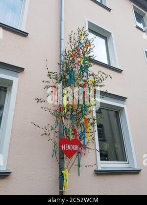 Vertikale Aufnahme einer Maibaum mit einem roten Herz auf Das Gebäude Stockfoto