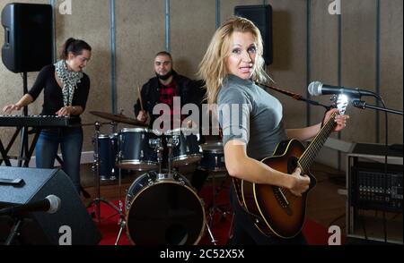 Musik Garagenband mit leidenschaftlicher emotionaler Sängerin und Gitarristin im Proberaum Stockfoto
