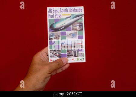 Penang, Malaysia - 25. Mai 2020 : Nahaufnahme einer Hand, die einen gebrauchten JR East South Hokkaido Rail Pass auf weißem Hintergrund bei Gelugor hält Stockfoto