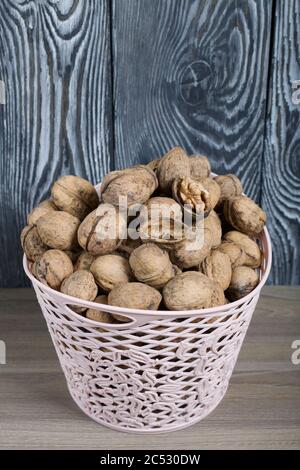 Korb mit Walnüssen. Vor dem Hintergrund von Kiefernholzplatten in schwarz und weiß gemalt. Ernte während der Pandemie 2020. Stockfoto