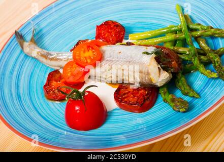 Fischgericht - Blauer Wittling gebacken mit Sun - tomaten, Spargel und cremige Knoblauchsauce getrocknet Stockfoto