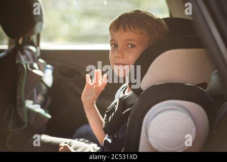 Lächelnder Junge im Auto winkt auf Wiedersehen Stockfoto