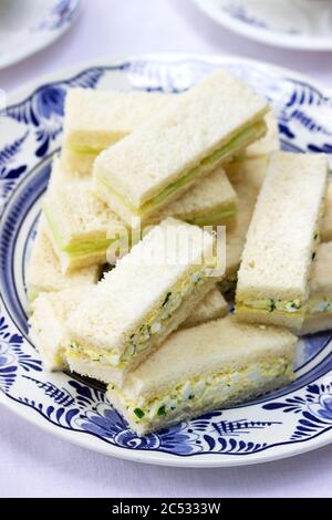 Nachmittagstee im Garten, Fingersandwiches mit Gurken und Eiersalat und Tee auf hellem Hintergrund. Stockfoto