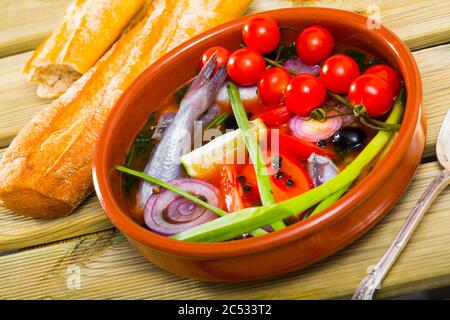 Fisher Suppe von Wittling mit Tomaten, roten Zwiebeln, Paprika, Frühlingszwiebeln mit Zitrone serviert, schwarze Oliven und frischem Brot Stockfoto