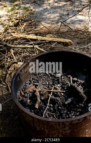 Verbrannte Holzkohle wird in einem sicheren Stahlbehälter abgelegt, um versehentliche Brände auf einem öffentlichen Campingplatz zu verhindern. Stockfoto