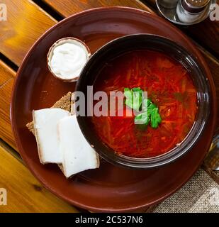 Leckere russische Gericht Borscht mit Brot, Schmalz slicrs und saurer Sahne serviert. Stockfoto