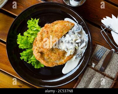 Leckere Schweineschnitzel paniert mit Champignons in Sahnesoße serviert. Stockfoto