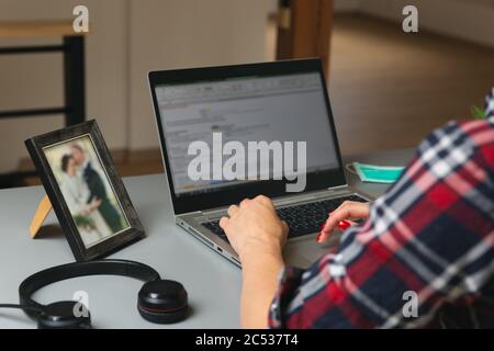 Junge Frauen, die von zu Hause aus arbeiten. Sitzen im Dachgeschoss mit Laptop in der Nähe von Dachfenster. Neues normales Konzept Stockfoto
