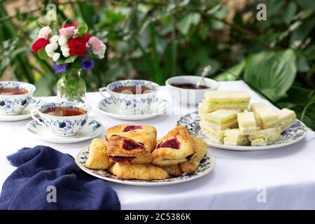Nachmittagstee im Garten mit Scones, Erdbeermarmelade, Fingerbrote mit Gurke und Eiersalat. Stockfoto