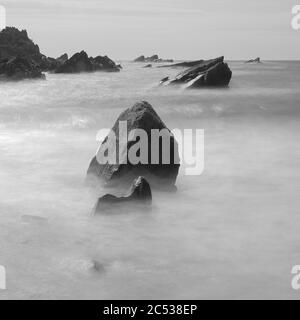 Felsen umgeben von verschwommenen Meereswellen an der Küste von North Devon, England Stockfoto
