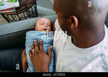 Neugeborenes Baby schläft in väterlichen Armen Stockfoto