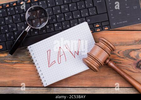 Close-up Gesetze Wörter auf Spiral Notizblock gavel und Lupe auf der Tastatur geschrieben. Stockfoto