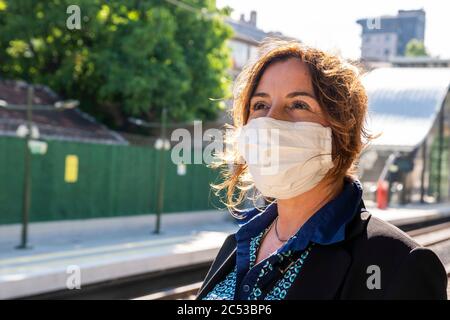 Frau Passagier mit Schutzmaske ist in einem Bahnhof warten. Stockfoto