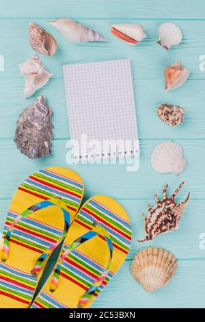 Flache Lay-Komposition mit Sandalen, Muscheln und Notizblock. Stockfoto
