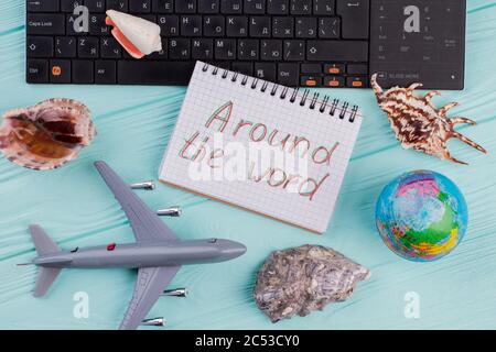 Flach Lay Reisekomposition mit Flugzeug, Globus, Muscheln und Notizblock auf blauem Schreibtisch. Stockfoto