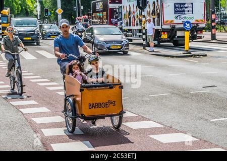 AMSTERDAM, NIEDERLANDE - 18. JULI 2018: Ein Mann, der mit seinen Kindern auf dem Fahrrad durch die Straßen Amsterdams fährt. Hochwertige Fotos Stockfoto