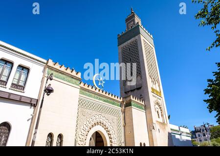 Blick in den Winkel des 33 Meter hohen Minaretts der Großen Moschee von Paris, Frankreich, mit dem Stern und der Sichel über dem Eingang gegen blauen Himmel. Stockfoto